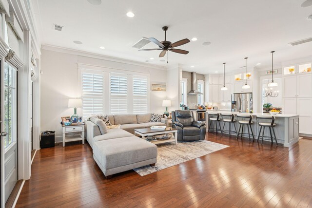 living room featuring ornamental molding, dark wood-style flooring, visible vents, and plenty of natural light