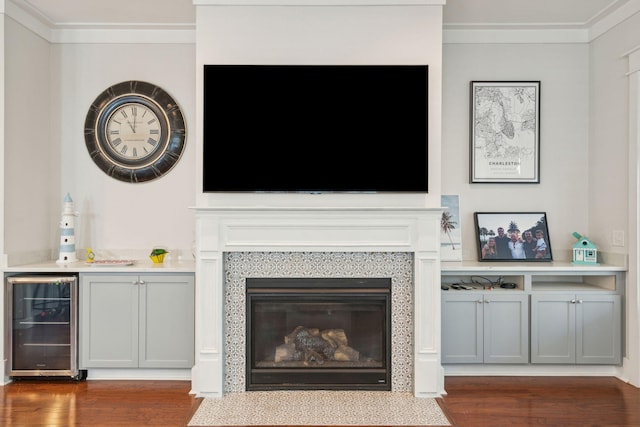 living area featuring ornamental molding, wine cooler, dark wood finished floors, and a fireplace with flush hearth