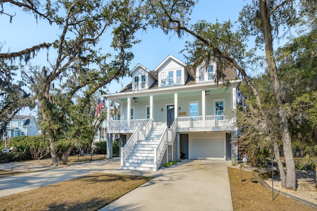 coastal inspired home with a garage, covered porch, driveway, and stairway