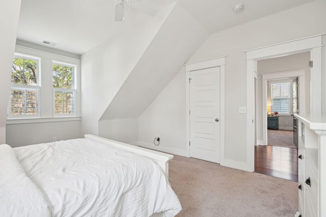 carpeted bedroom with lofted ceiling, visible vents, baseboards, and multiple windows