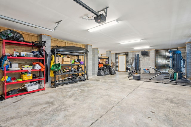 garage featuring concrete block wall and a garage door opener