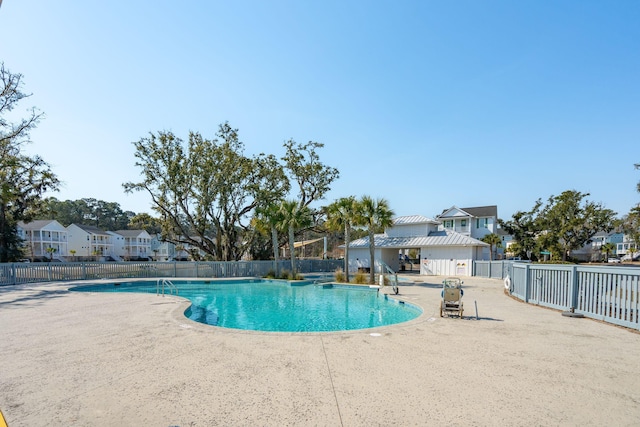 community pool with a residential view, a patio, and fence