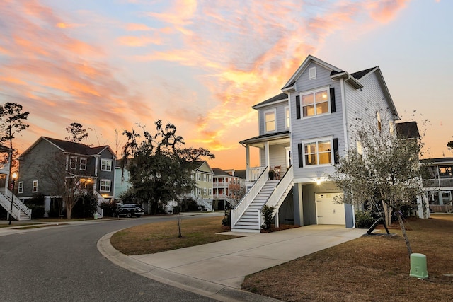 view of front of property featuring a residential view, driveway, stairway, and an attached garage