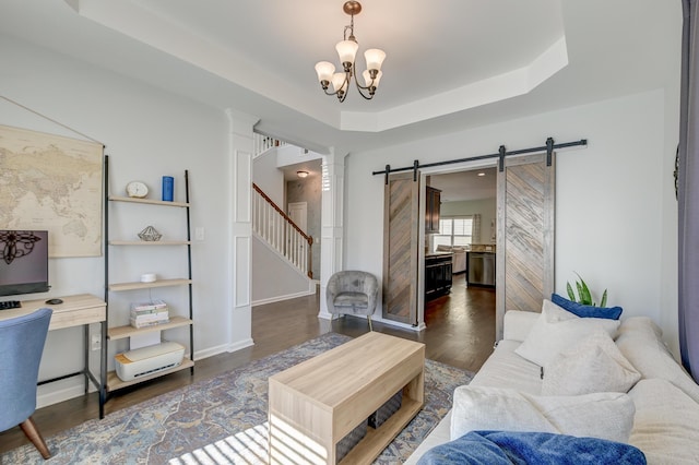 living area with dark wood finished floors, a raised ceiling, a barn door, a chandelier, and stairs