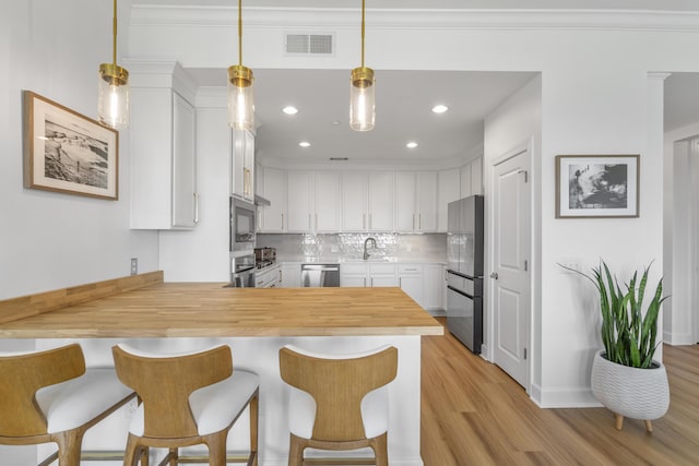 145 Pier View St Unit 407, Charleston, SC 29492 - kitchen featuring stainless steel appliances, a peninsula, light wood finished floors, decorative backsplash, and a sink