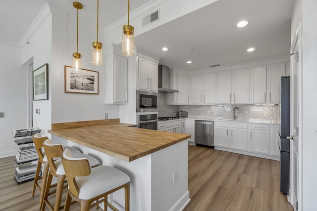 145 Pier View St Unit 407, Charleston, SC 29492 - kitchen with stainless steel appliances, a peninsula, wooden counters, ornamental molding, and light wood-type flooring
