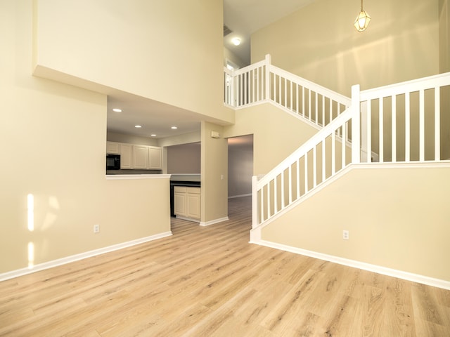 unfurnished living room with light hardwood / wood-style flooring and a high ceiling