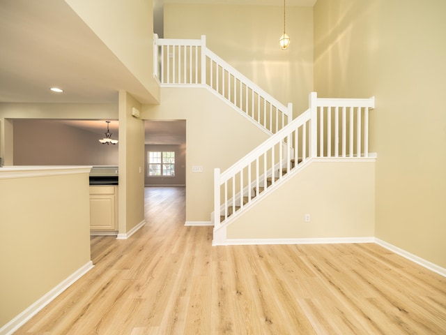 stairway with wood-type flooring, a chandelier, and a high ceiling