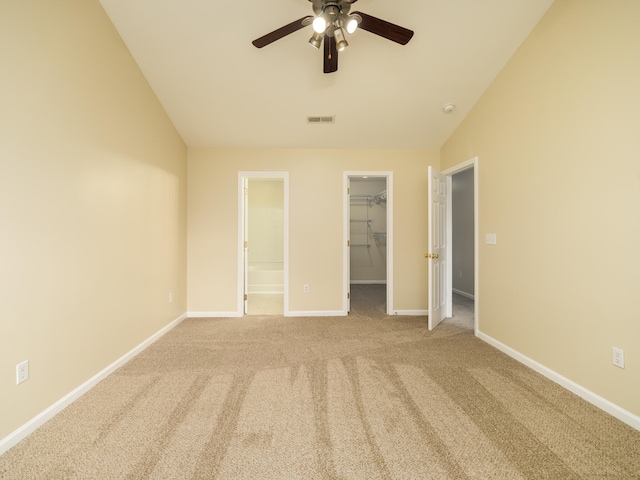 unfurnished bedroom with lofted ceiling, a spacious closet, carpet, and ceiling fan