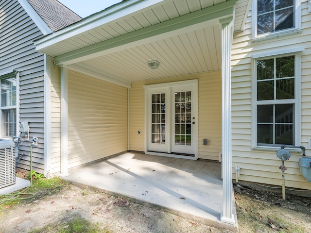 view of exterior entry featuring central AC unit and a patio