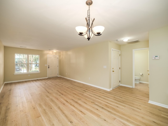 unfurnished room with a notable chandelier and light wood-type flooring