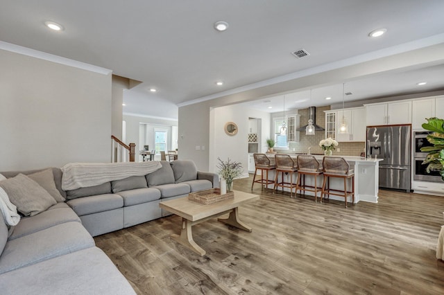 living room featuring crown molding, recessed lighting, wood finished floors, and visible vents