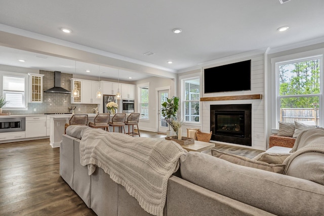 living room featuring recessed lighting, a large fireplace, dark wood-style floors, and crown molding