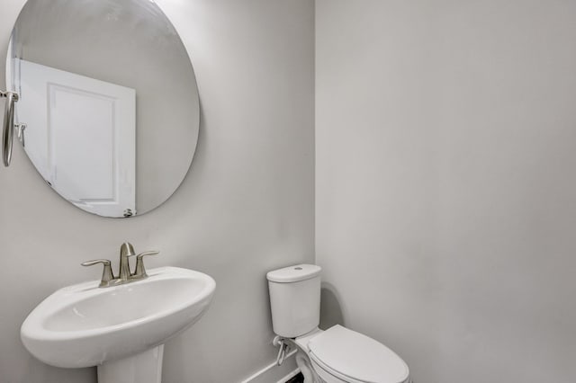 bathroom with a sink, baseboards, and toilet