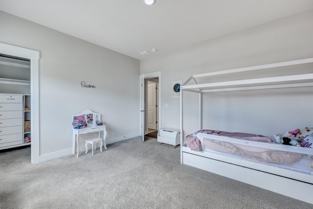 carpeted bedroom featuring a walk in closet and baseboards