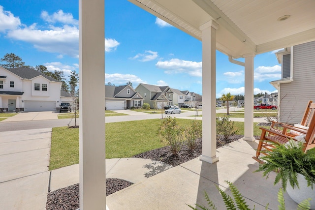 view of patio / terrace with a garage, covered porch, and a residential view