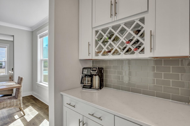 bar featuring decorative backsplash, a wealth of natural light, light wood finished floors, and ornamental molding