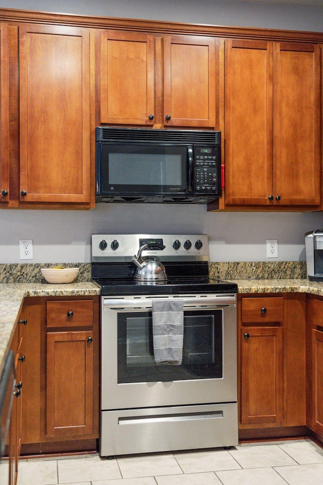 kitchen with light stone counters, brown cabinets, stainless steel electric range, and black microwave