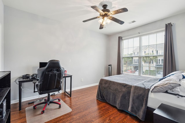 bedroom with ceiling fan, wood finished floors, visible vents, and baseboards