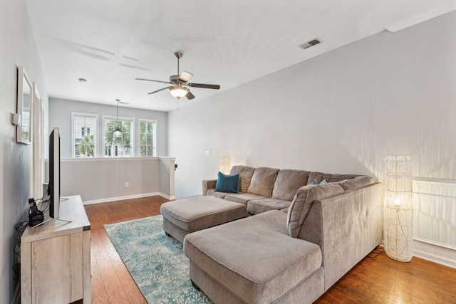 living area featuring baseboards, visible vents, wood-type flooring, and ceiling fan