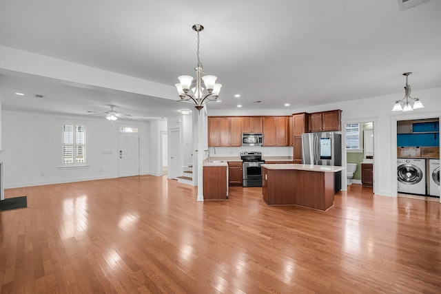 kitchen featuring decorative light fixtures, independent washer and dryer, a kitchen island, and stainless steel appliances