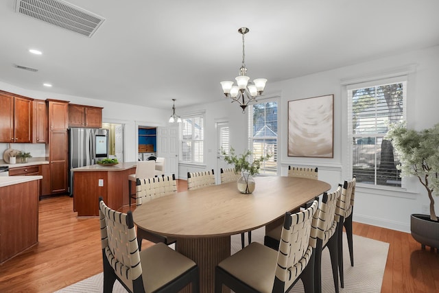 dining area featuring light wood-type flooring and an inviting chandelier