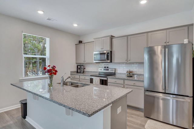 kitchen with light stone countertops, stainless steel appliances, gray cabinets, and sink