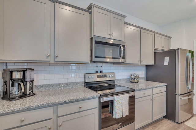 kitchen with decorative backsplash, light stone countertops, and stainless steel appliances