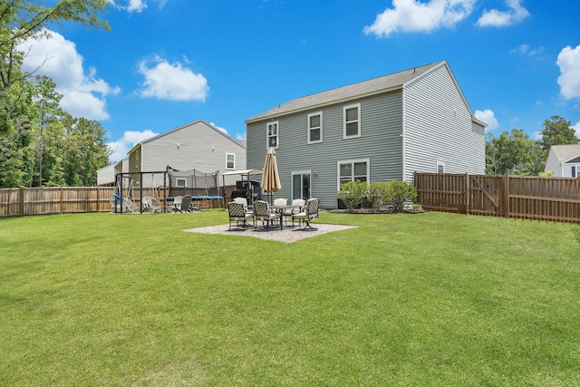 back of house featuring a yard, a trampoline, and a patio area