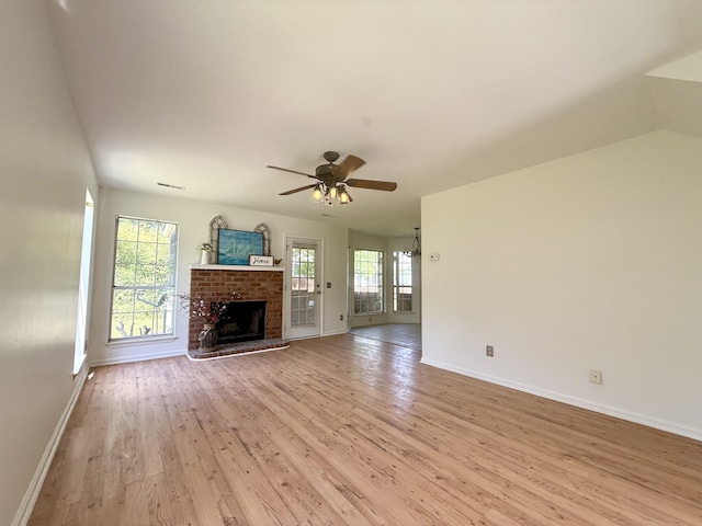 unfurnished living room with a ceiling fan, visible vents, a fireplace, baseboards, and light wood finished floors
