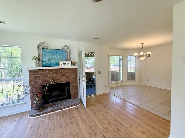 unfurnished living room with baseboards, an inviting chandelier, a wealth of natural light, and a fireplace
