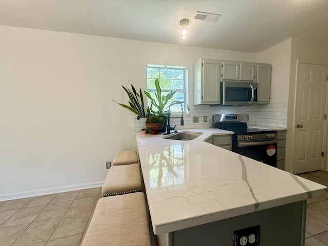 kitchen with a sink, stainless steel appliances, baseboards, tasteful backsplash, and visible vents
