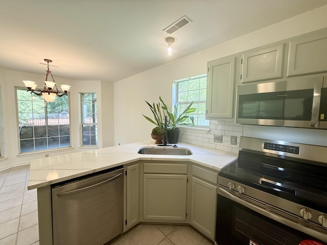 kitchen with light tile patterned flooring, a sink, stainless steel appliances, a peninsula, and visible vents