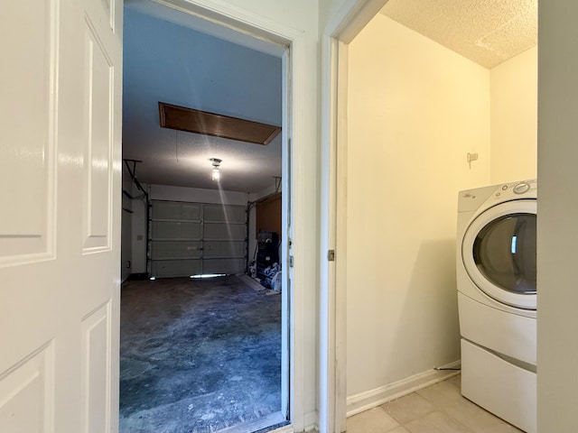 washroom featuring laundry area, washer / dryer, baseboards, a garage, and a textured ceiling