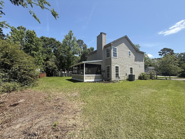 back of property featuring central AC, fence, a chimney, a sunroom, and a lawn