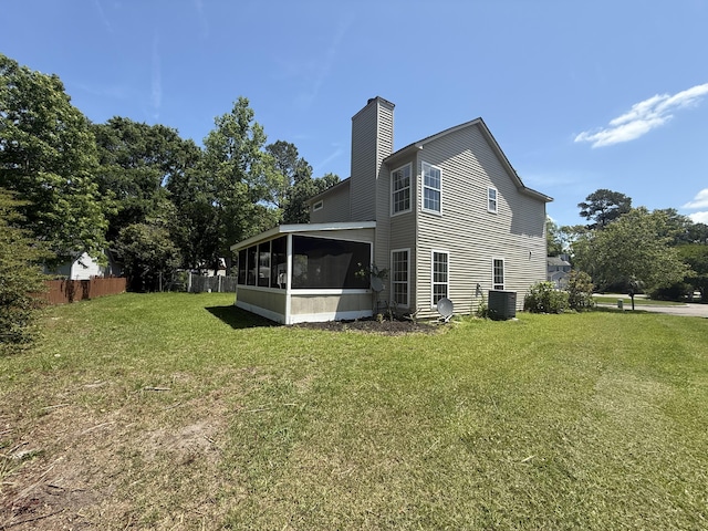 back of property featuring fence, central AC, a sunroom, a chimney, and a lawn