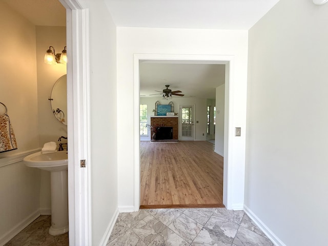 hall with baseboards, a sink, and marble finish floor