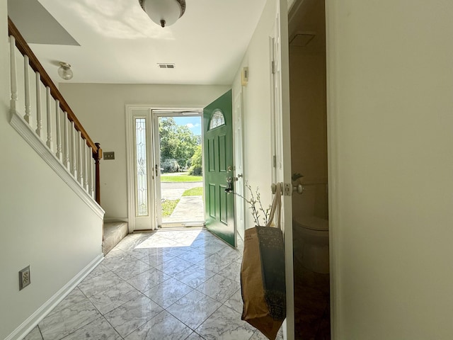 foyer entrance with baseboards, visible vents, stairs, and marble finish floor