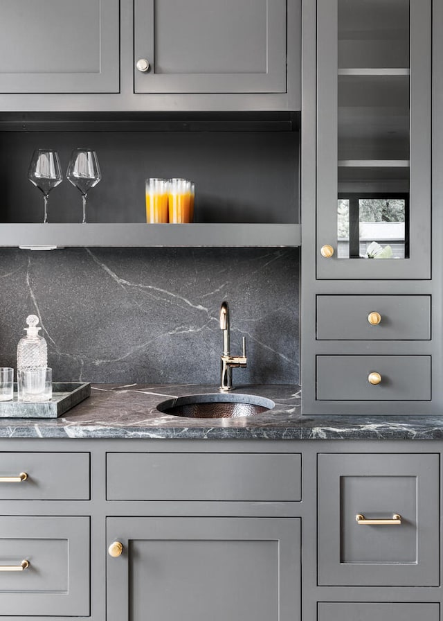 bar featuring gray cabinets, tasteful backsplash, and sink