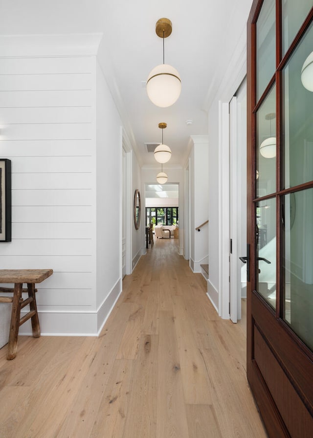 hall with crown molding and light hardwood / wood-style floors