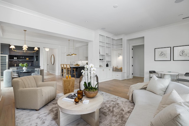 living room with ornamental molding, light hardwood / wood-style floors, and built in shelves