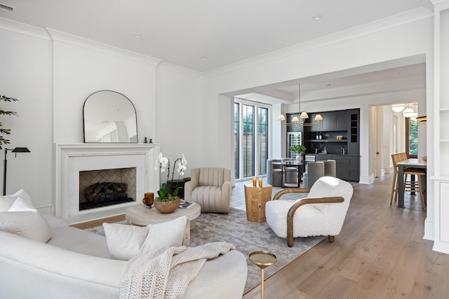 living room with crown molding, light hardwood / wood-style floors, and a chandelier