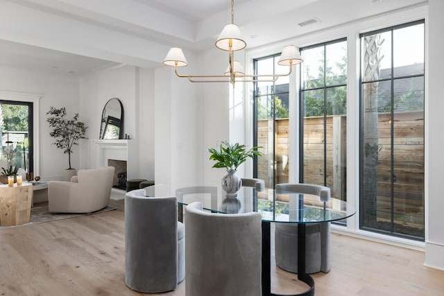 dining space with light hardwood / wood-style floors and a notable chandelier