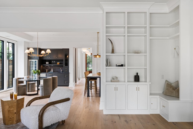 dining area featuring built in shelves, a chandelier, and light hardwood / wood-style floors