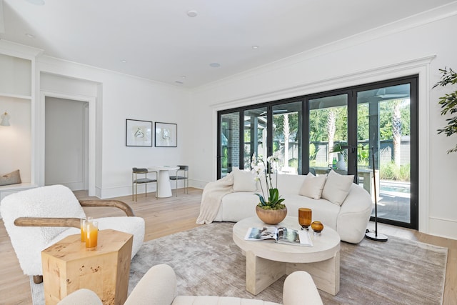 living room featuring crown molding, a healthy amount of sunlight, and light wood-type flooring