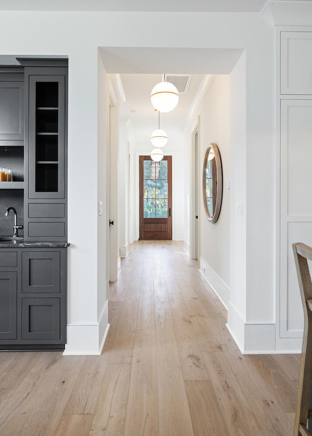 corridor featuring sink, ornamental molding, and light hardwood / wood-style floors