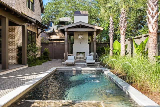 view of pool with an outdoor fireplace, pool water feature, and a patio