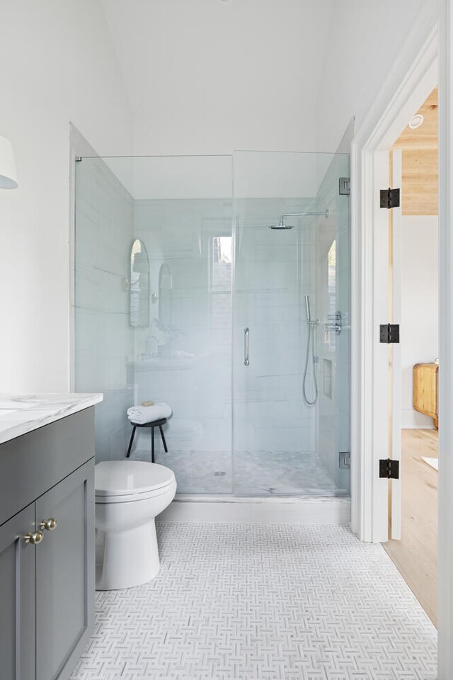 bathroom featuring tile patterned floors, vanity, toilet, and an enclosed shower