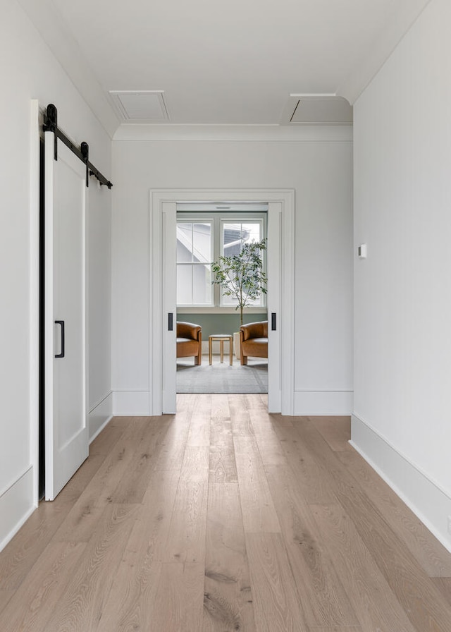 corridor featuring light hardwood / wood-style floors and a barn door