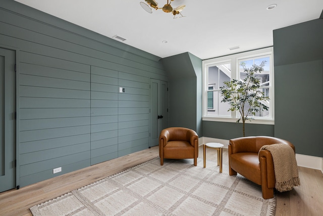 living area featuring light hardwood / wood-style floors and wood walls